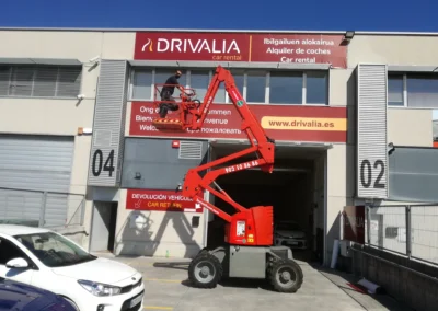 Instalación de rótulo corporativo de fachada de Drivalia en una nave o fachada industrial con brazo articulado.
