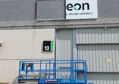 Instalación de rótulo corporativo de fachada de EON en una nave o fachada industrial con plataforma elevadora.