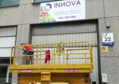 Instalación de rótulo de nave de Innova Sport en una nave o fachada industrial con plataforma de tijera.