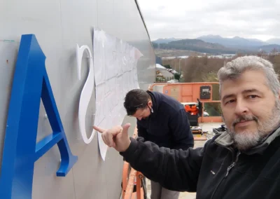 Instalación de letras corpóreas de Jumasa en una nave o fachada industrial con plataforma elevadora.