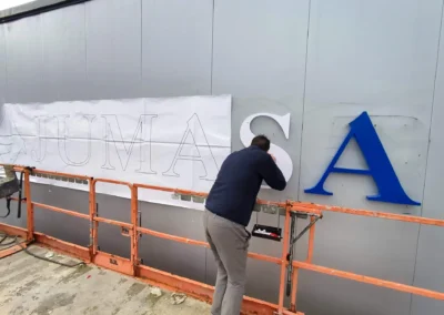 Instalación de letras corpóreas de Jumasa en una nave o fachada industrial con plataforma elevadora.