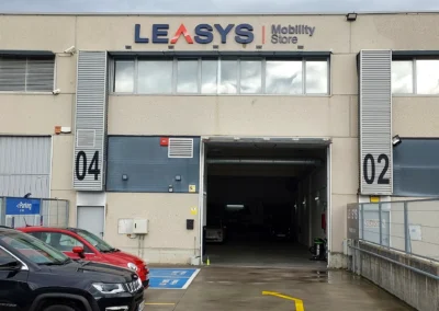 Rótulo corporativo de fachada de LEASYS Mobility Store terminado en una nave o fachada industrial.
