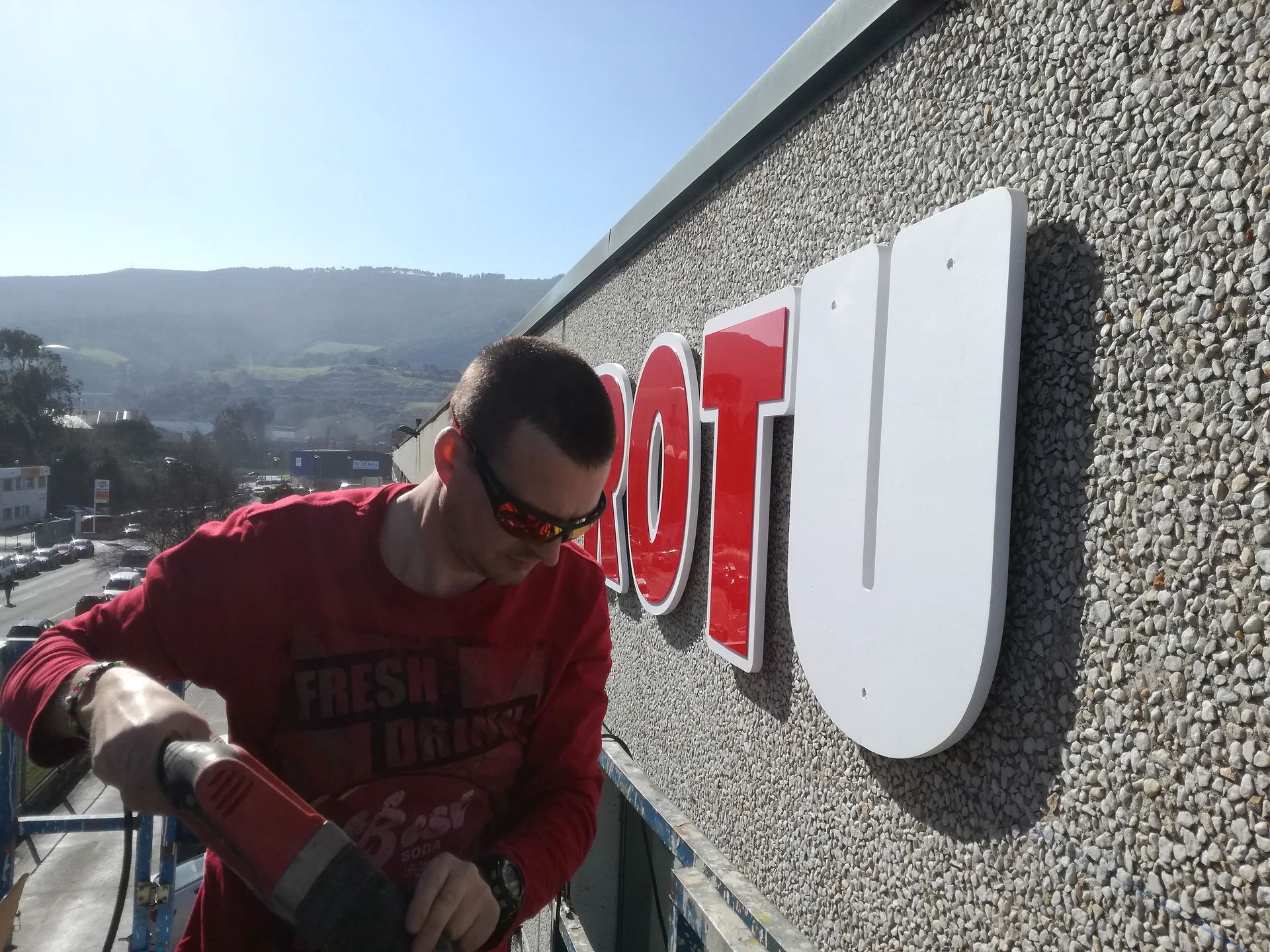 Instalación de letras corpóreas en altura en una fachada industrial.