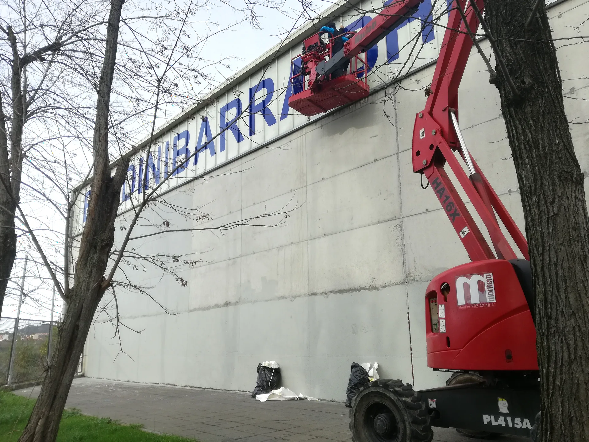 Instalación de letras corpóreas de gran tamaño en una nave con plataforma elevadora.