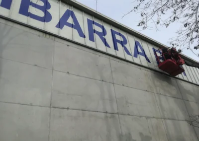 Instalación de letras corpóreas de gran tamaño en una nave o fachada industrial con brazo articulado.