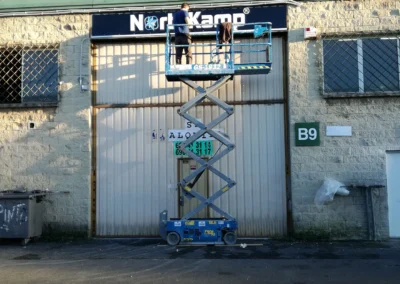Instalación de rótulo de nave de NorthKamp en una nave o fachada industrial con plataforma de tijera.