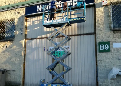 Instalación de rótulo de nave de NorthKamp en una nave o fachada industrial con plataforma de tijera.