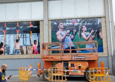 Paneles gráficos de gran formato de centro deportivo terminados en una nave o fachada industrial.