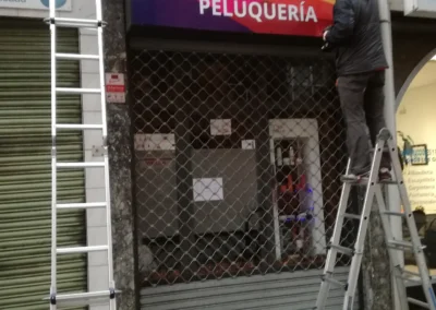Instalación de rótulo comercial de Andrea Blanco Peluquería en una fachada comercial con escaleras.