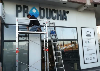 Instalación de letras y rótulo comercial de Producha en una fachada comercial con andamio y escalera.