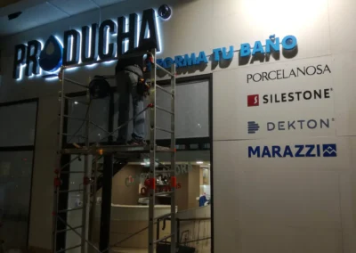 Instalación de letras y rótulo comercial de Producha en una fachada comercial con andamio.