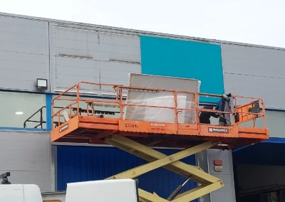 Instalación de rótulo corporativo de gran formato de Revenant en una nave o fachada industrial con plataforma de tijera.