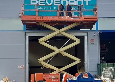 Instalación de rótulo corporativo de gran formato de Revenant en una nave o fachada industrial con plataforma de tijera.