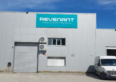 Rótulo corporativo de gran formato de Revenant terminado en una nave o fachada industrial.
