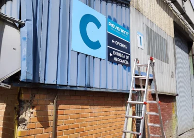 Instalación de señalética industrial de Revenant en una nave o fachada industrial con escalera.