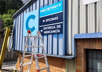 Instalación de señalética industrial de Revenant en una nave o fachada industrial con escalera.