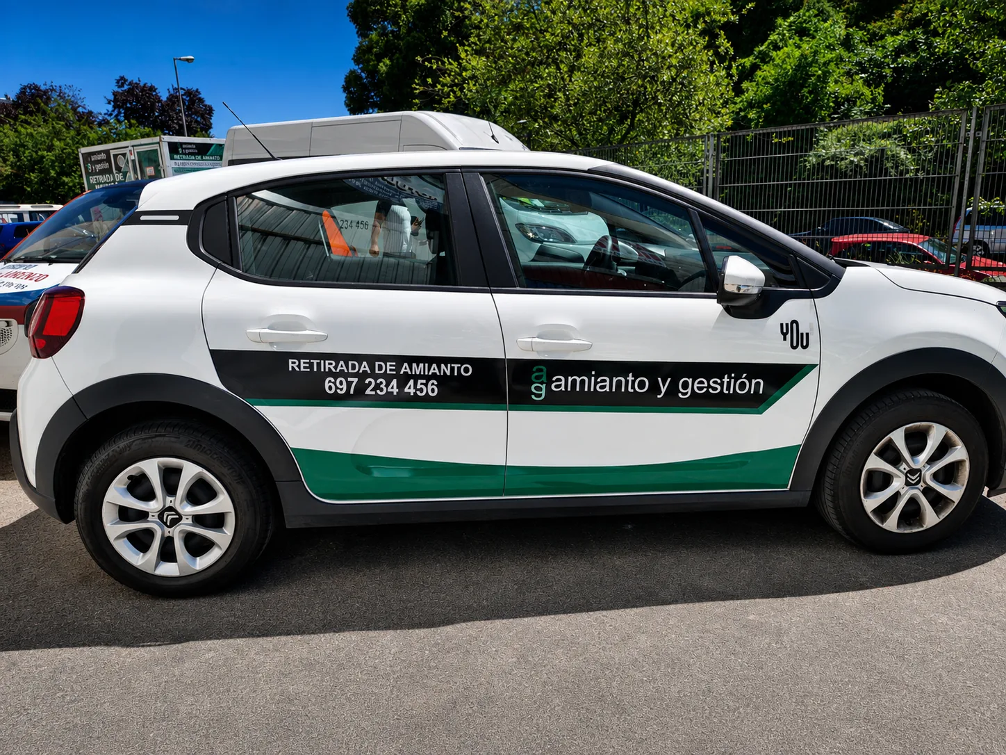 Coche comercial blanco con rotulación corporativa negra y verde para empresa de retirada de amianto
