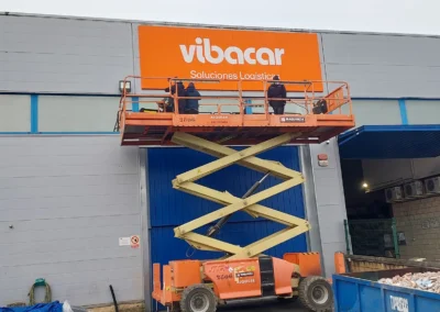 Instalación de rótulo corporativo de gran formato de Vibacar en una nave o fachada industrial con plataforma de tijera.