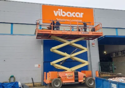 Instalación de rótulo corporativo de gran formato de Vibacar en una nave o fachada industrial con plataforma de tijera.